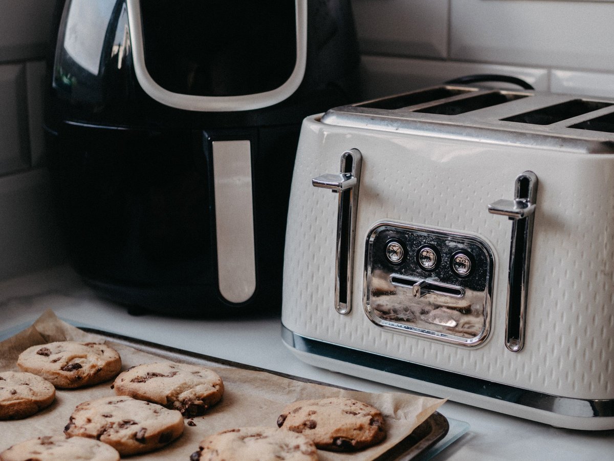 Basket air fryer on a kitchen counter next to a toaster and fresh-baked cookies