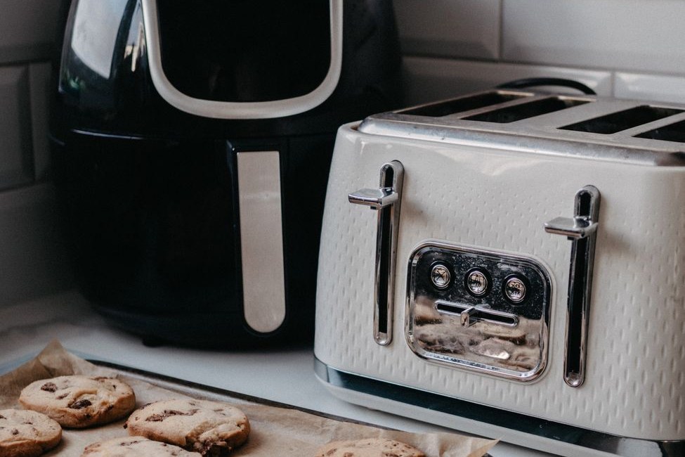 Countertop air fryer on a kitchen counter next to a tray of freshly baked cookies