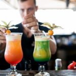 Bartender garnishing vibrant fresh cocktails at a home bar counter