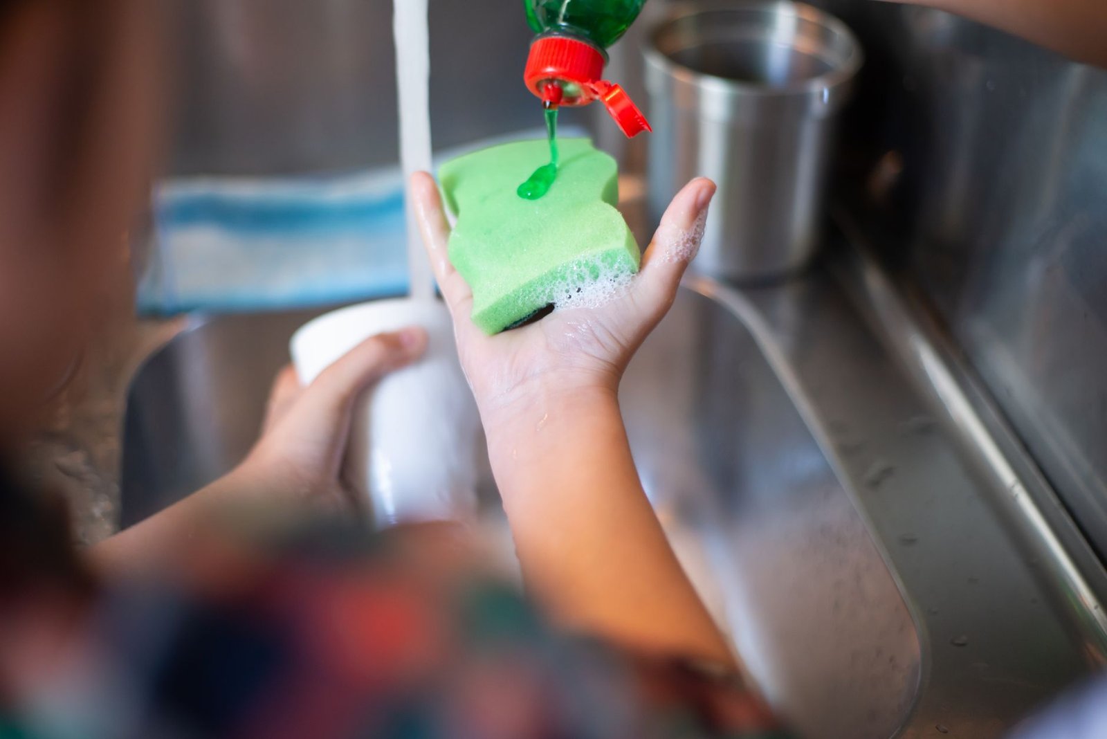 Adding dish soap to a sponge to clean an air fryer basket