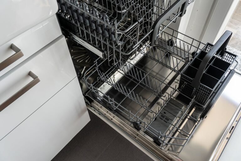 Open stainless steel countertop dishwasher in a modern apartment kitchen