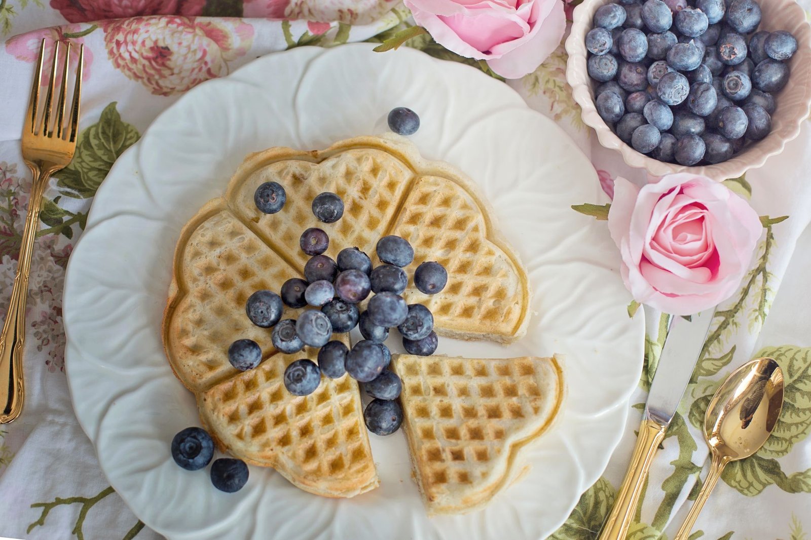 Homemade mini waffles topped with fresh blueberries on a plate