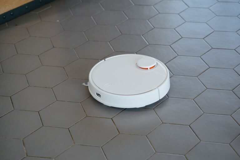 White robot vacuum cleaner navigating a floor, illustrating the 2026 FCC robot vacuum ban buying guide