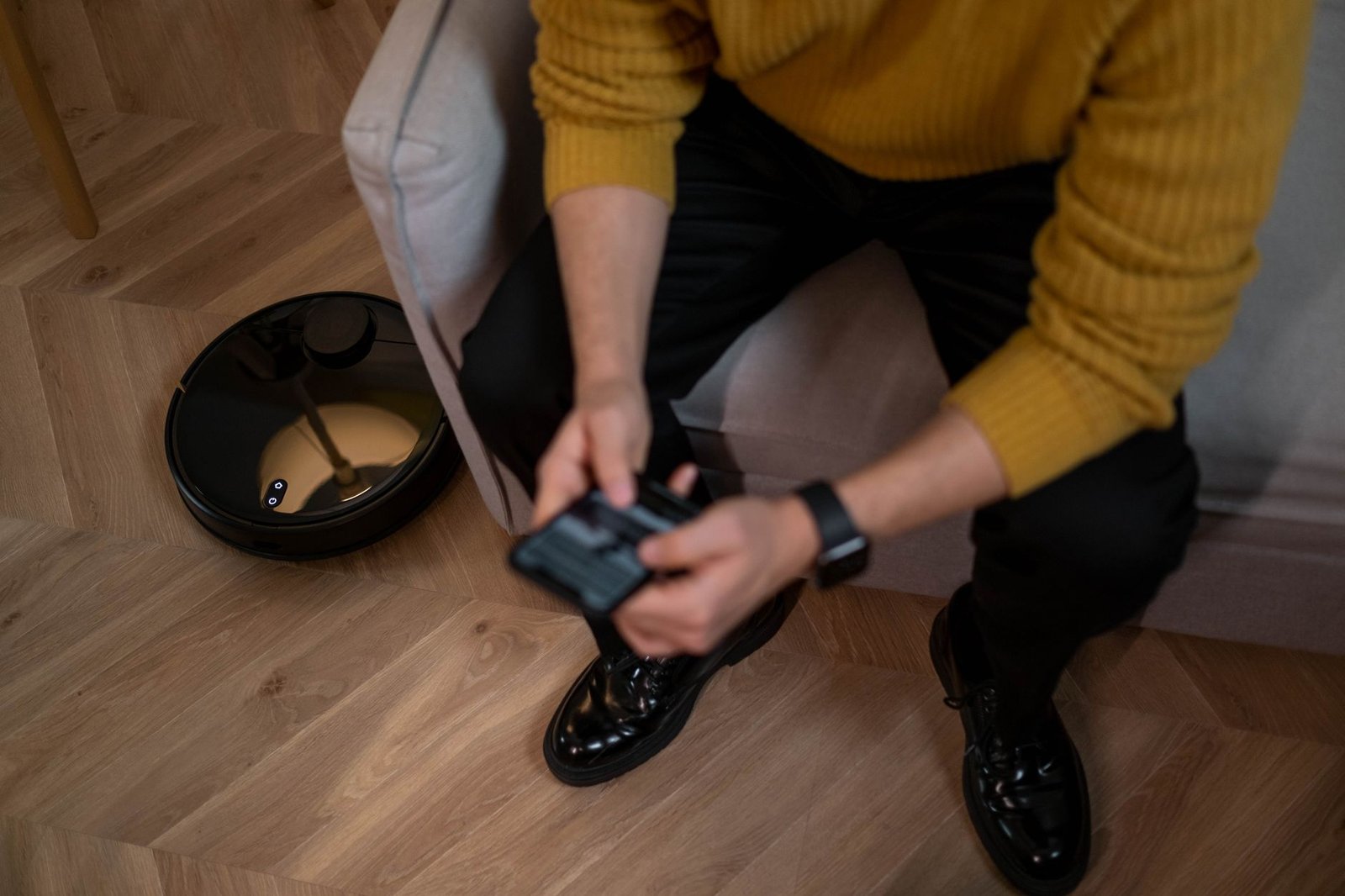 Person using a phone app to control a robot vacuum cleaner in a home