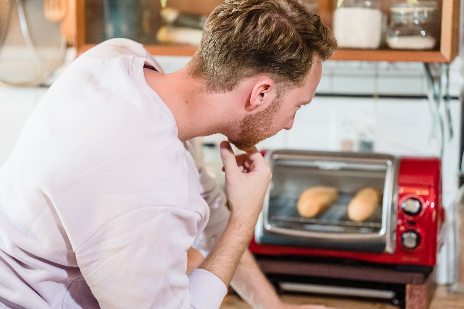 Person watching bread bake in a toaster oven in a home kitchen