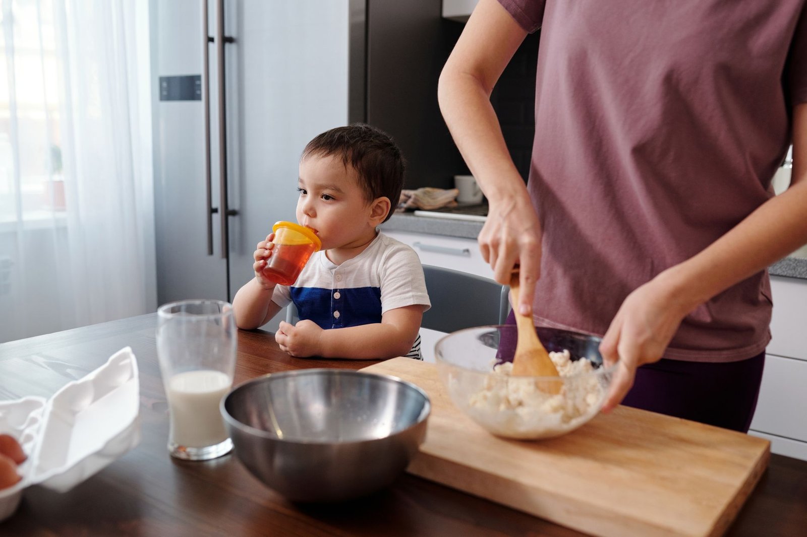 Young child kneading dough beside a parent at the kitchen counter, the kind of task a stable learning tower enables