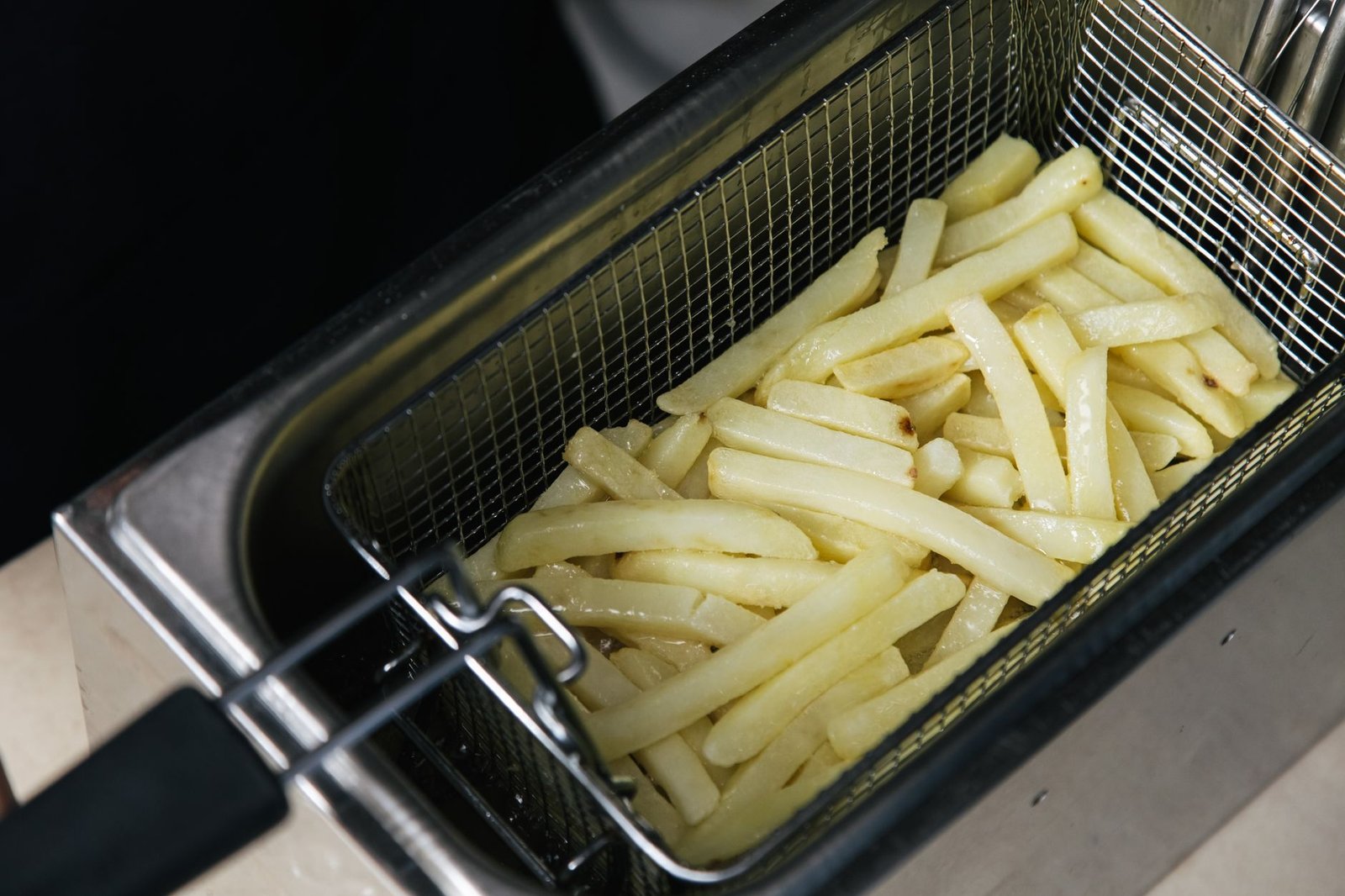 Voice-controlled air fryer cooking food with the basket open in a home kitchen